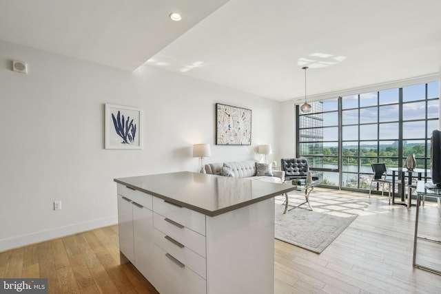 kitchen with light wood-style flooring, a center island, modern cabinets, white cabinetry, and dark countertops