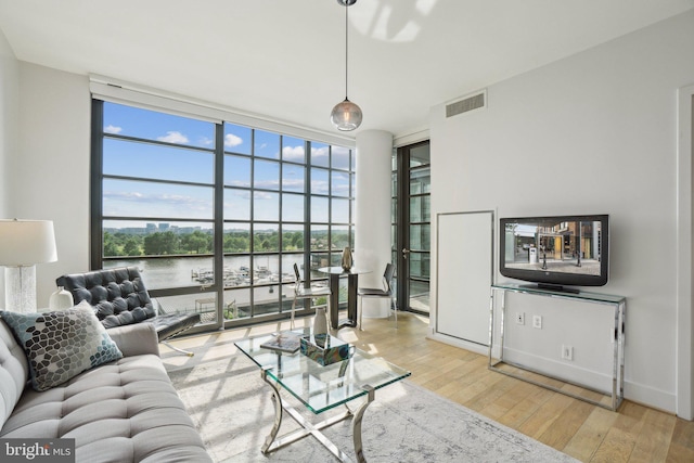 living room with visible vents, floor to ceiling windows, and wood finished floors