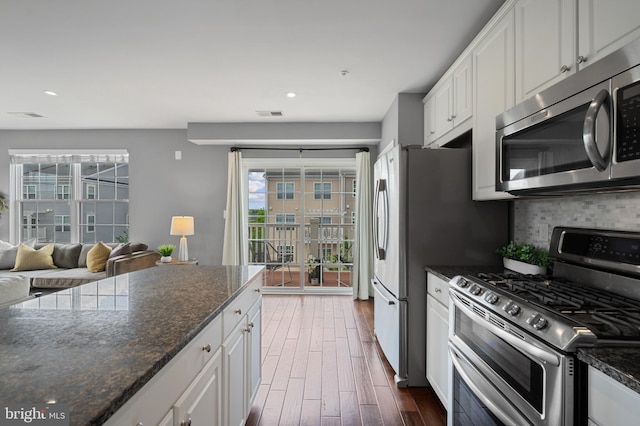 kitchen with appliances with stainless steel finishes, recessed lighting, tasteful backsplash, plenty of natural light, and white cabinets