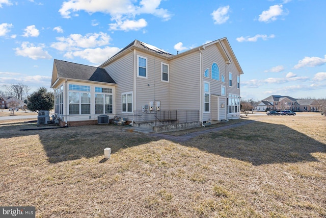 rear view of house featuring central AC and a yard