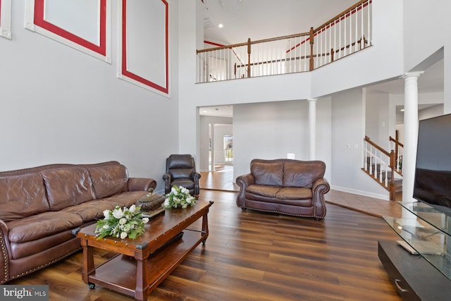 living area with wood finished floors, decorative columns, a high ceiling, and stairway