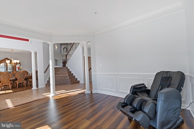 sitting room with dark wood finished floors, a wainscoted wall, and decorative columns