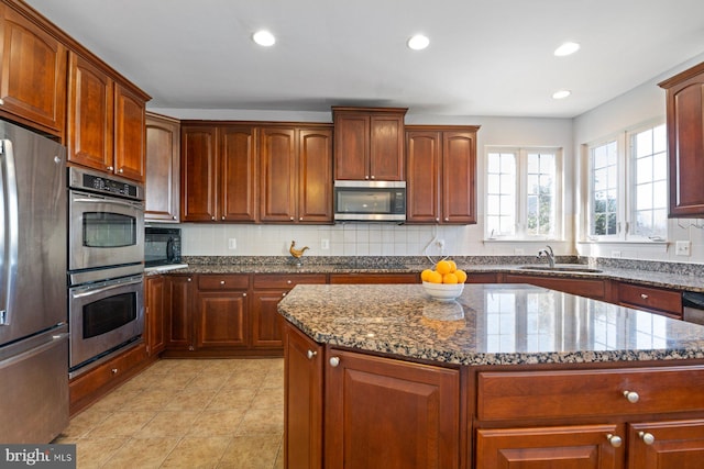 kitchen with dark stone counters, black appliances, backsplash, and a sink
