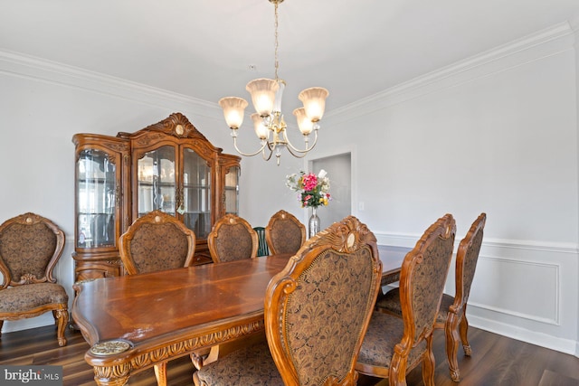 dining room with a wainscoted wall, dark wood finished floors, a notable chandelier, and crown molding