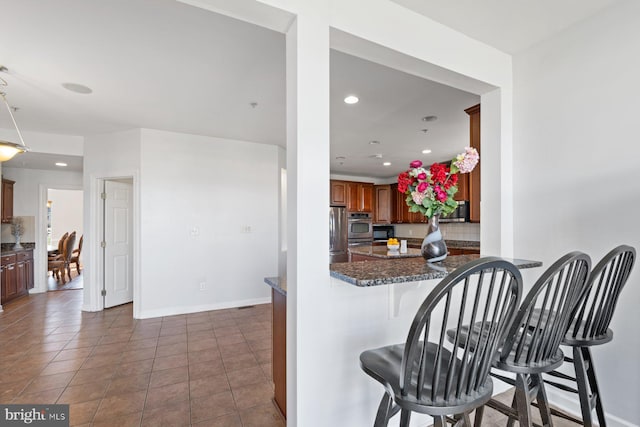 kitchen with a breakfast bar area, baseboards, appliances with stainless steel finishes, and recessed lighting