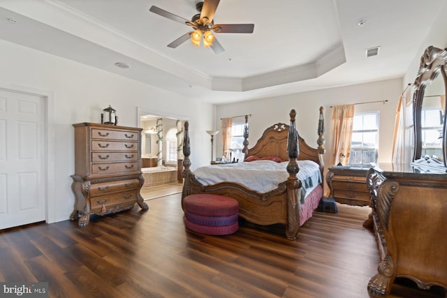 bedroom featuring multiple windows, wood finished floors, visible vents, and a tray ceiling