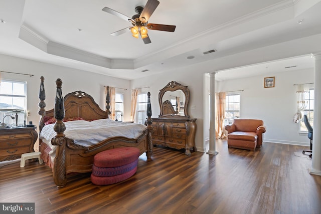 bedroom with a tray ceiling, ornate columns, and crown molding