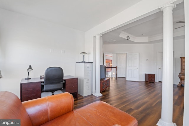 office space featuring ornamental molding, dark wood-style flooring, a tray ceiling, and decorative columns