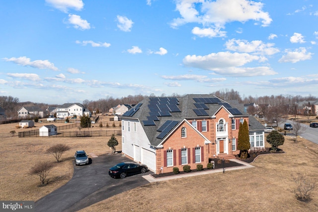 view of front of house featuring driveway, fence, a garage, solar panels, and brick siding