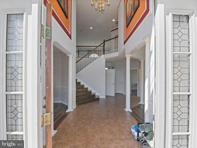 foyer featuring stairway, recessed lighting, a notable chandelier, and ornate columns