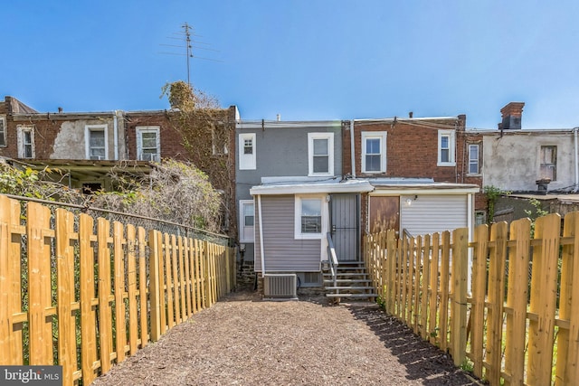 back of house featuring brick siding, a fenced backyard, central AC unit, and entry steps