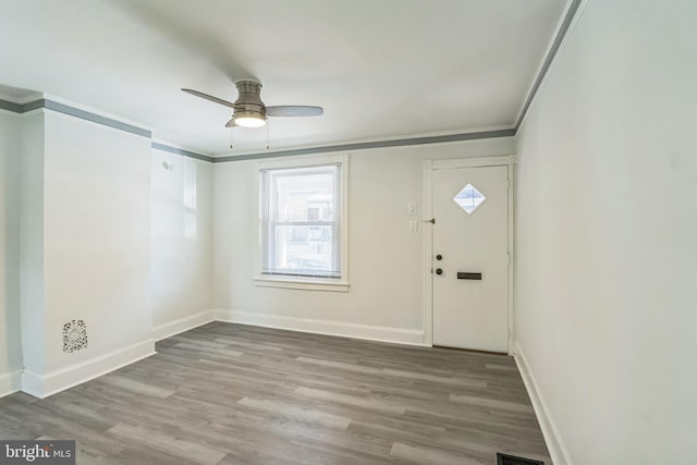foyer with baseboards, ornamental molding, a ceiling fan, and wood finished floors