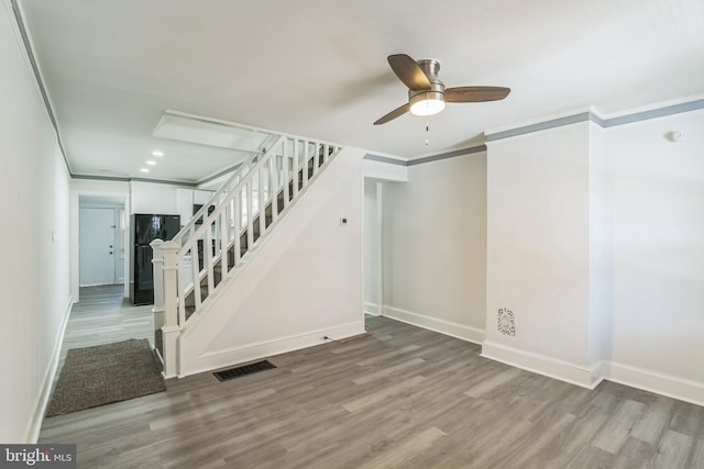 interior space with visible vents, crown molding, wood finished floors, baseboards, and a ceiling fan