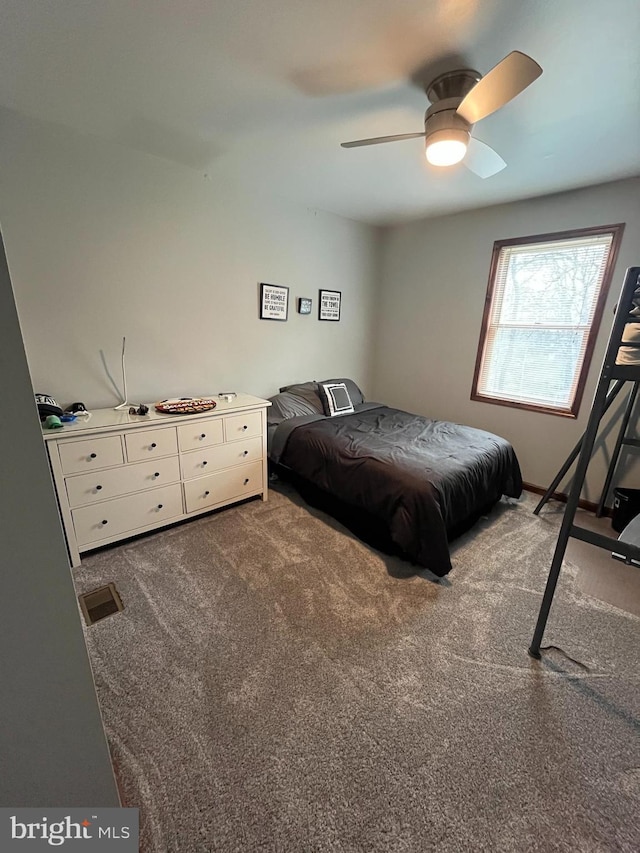 bedroom featuring dark colored carpet, visible vents, and a ceiling fan