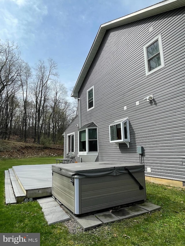 back of house featuring a hot tub and a deck