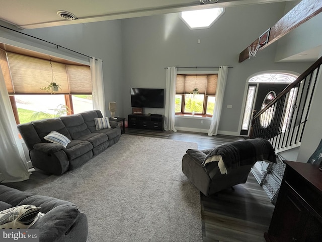 living area with visible vents, baseboards, wood finished floors, and a high ceiling