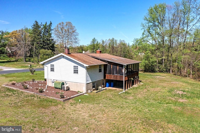 back of house featuring a chimney, a sunroom, and a yard