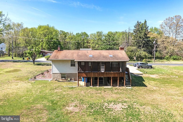 rear view of property featuring a chimney, a wooden deck, stairway, and a lawn