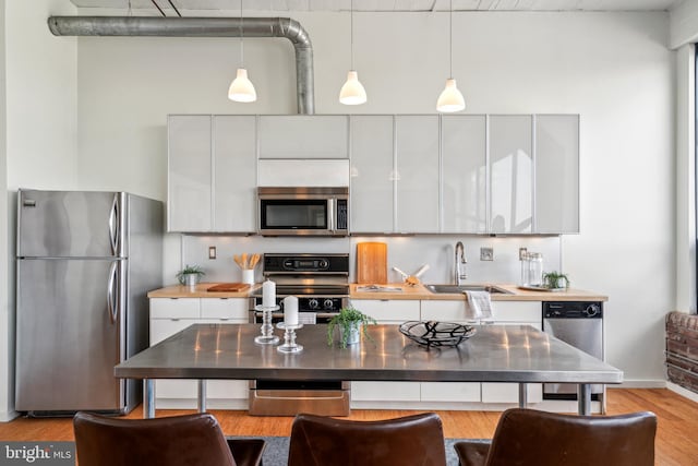 1714 Memphis St Unit 212, Philadelphia, PA 19125 - kitchen featuring stainless steel appliances, a sink, pendant lighting, white cabinetry, and light wood-style flooring