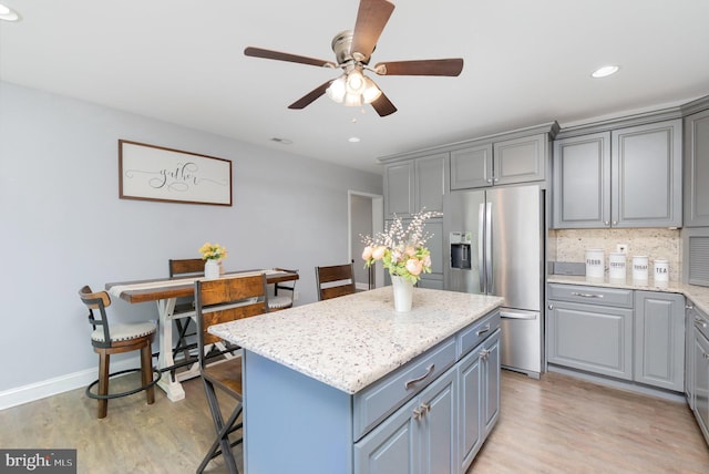 kitchen with light wood-style floors, ceiling fan, stainless steel fridge, a center island, and gray cabinetry
