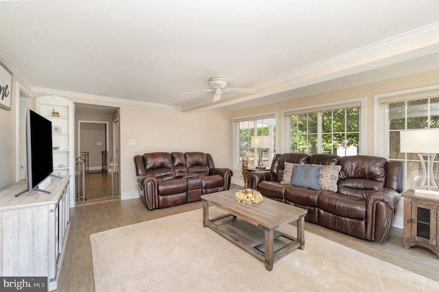 living area with light wood-style floors, ornamental molding, and a ceiling fan