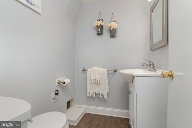 half bathroom with visible vents, wood finished floors, vanity, baseboards, and toilet