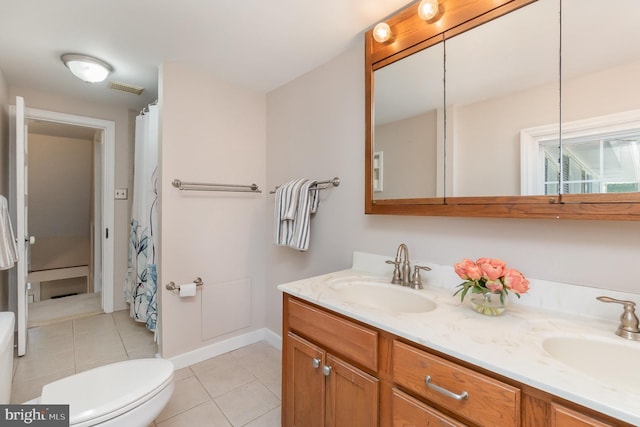 bathroom with a sink, tile patterned floors, toilet, and double vanity