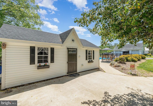 bungalow-style house with a patio, a shingled roof, and fence