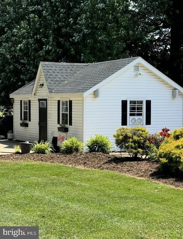 view of front facade featuring roof with shingles and a front lawn