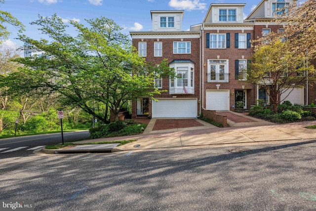 townhome / multi-family property with brick siding, driveway, and a garage