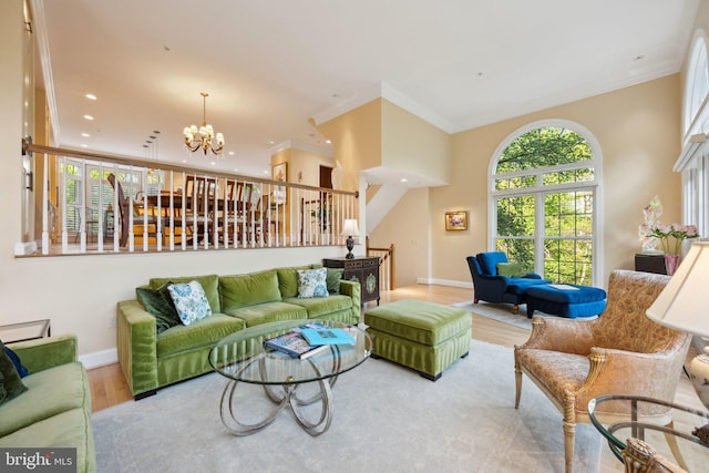 living area with a chandelier, wood finished floors, baseboards, and ornamental molding