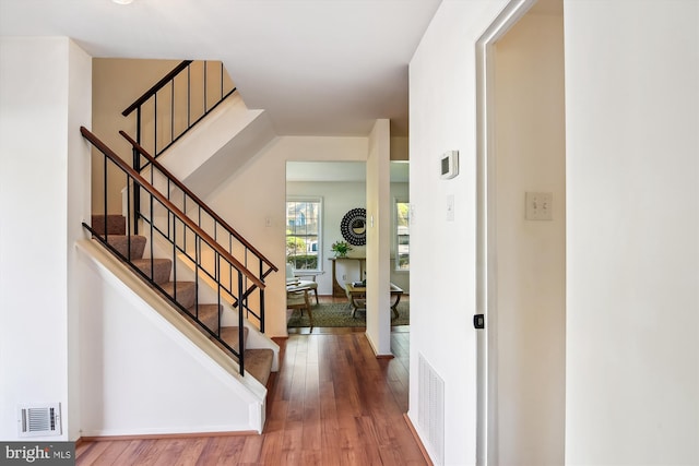 foyer entrance featuring visible vents, wood finished floors, and stairway