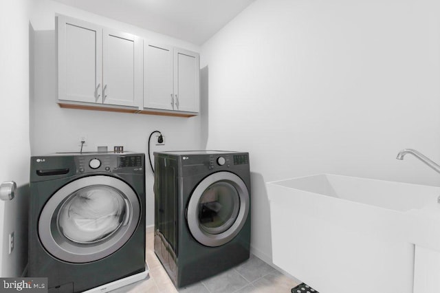 laundry area with light tile patterned floors, independent washer and dryer, and cabinet space