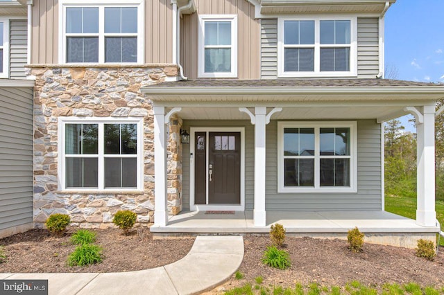 view of exterior entry featuring a porch, board and batten siding, and stone siding