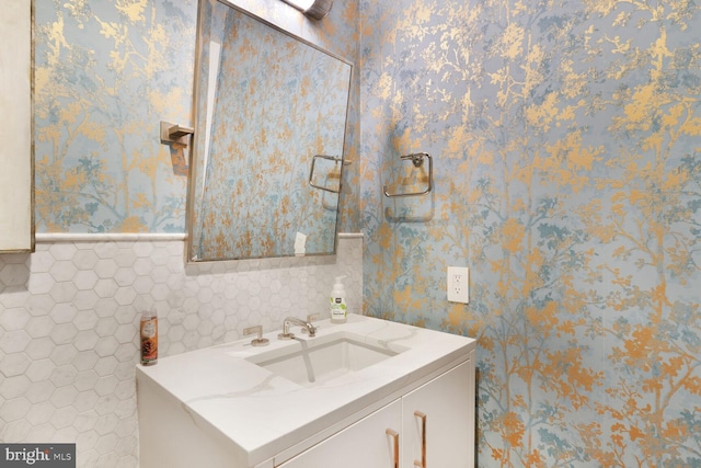 bathroom with vanity, wainscoting, and wallpapered walls