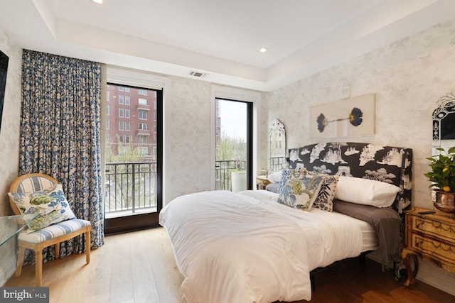 bedroom featuring access to exterior, wood finished floors, and visible vents