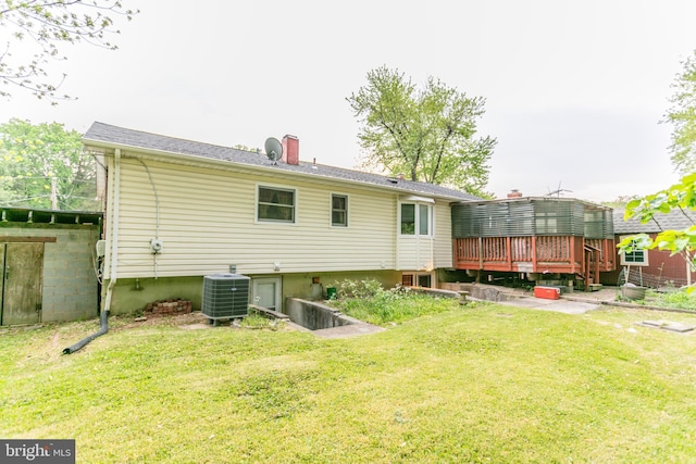 back of property featuring a lawn, central AC, a wooden deck, and a chimney