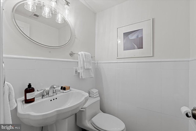 bathroom featuring tile walls, toilet, and a sink