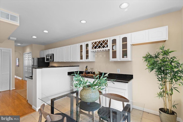 kitchen featuring dark countertops, visible vents, glass insert cabinets, and appliances with stainless steel finishes