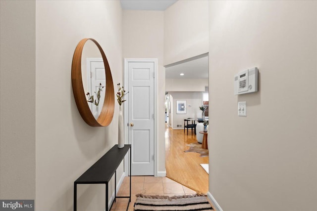 foyer entrance featuring baseboards, light tile patterned flooring, and a towering ceiling