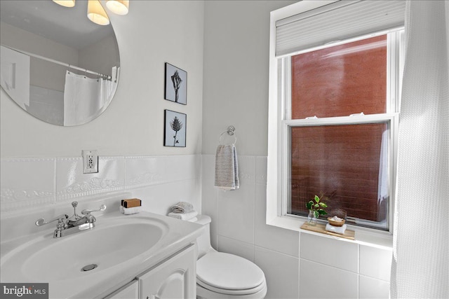full bath with tile walls, vanity, and toilet