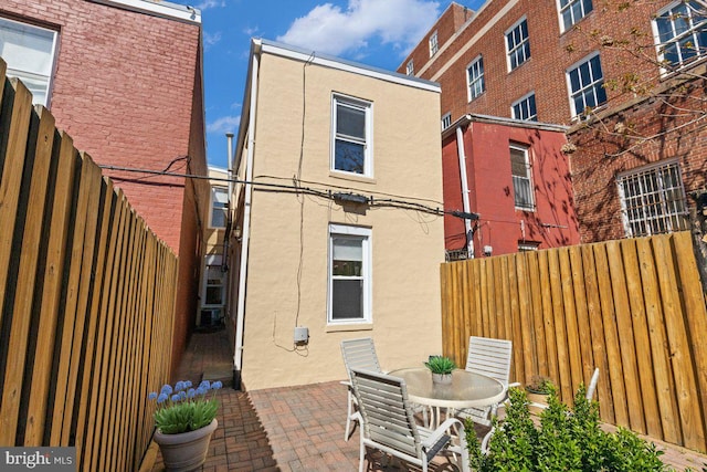 rear view of property featuring a patio area, stucco siding, and fence
