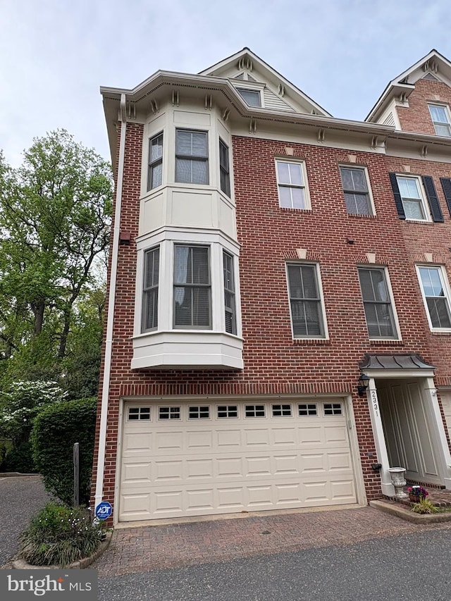 view of front of property with an attached garage, aphalt driveway, and brick siding