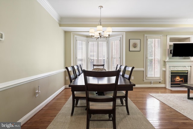 dining room featuring a chandelier, ornamental molding, a healthy amount of sunlight, and wood finished floors