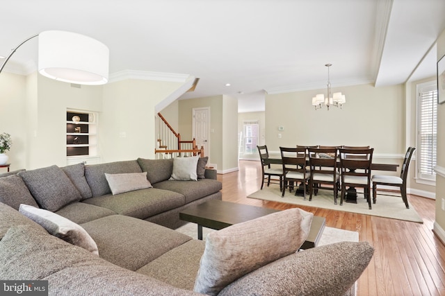living room featuring an inviting chandelier, a healthy amount of sunlight, stairway, and light wood-type flooring