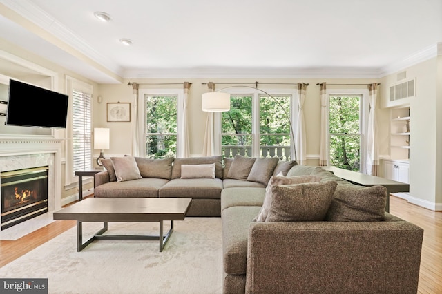 living area featuring visible vents, ornamental molding, a wealth of natural light, and a fireplace