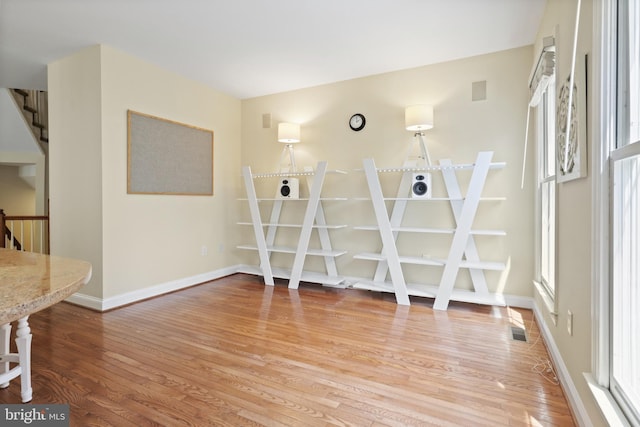 empty room with baseboards, visible vents, light wood finished floors, and stairs
