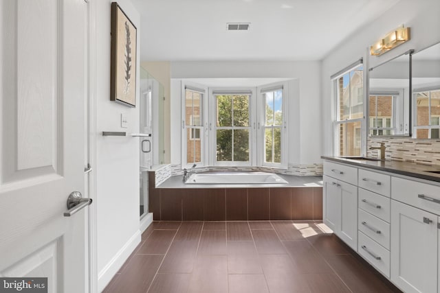 bathroom featuring visible vents, a bath, a stall shower, and vanity