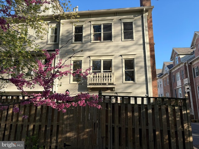 back of house with fence and a chimney