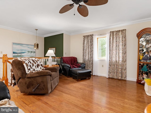 living room featuring ceiling fan, light wood-type flooring, crown molding, and baseboards